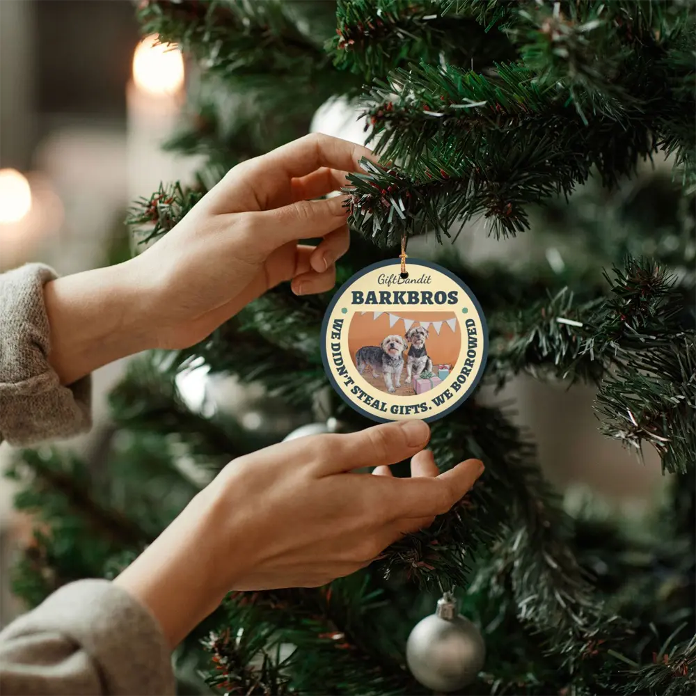 Custom ceramic photo ornament hanging on a Christmas tree with hands placing it as a meaningful holiday decoration