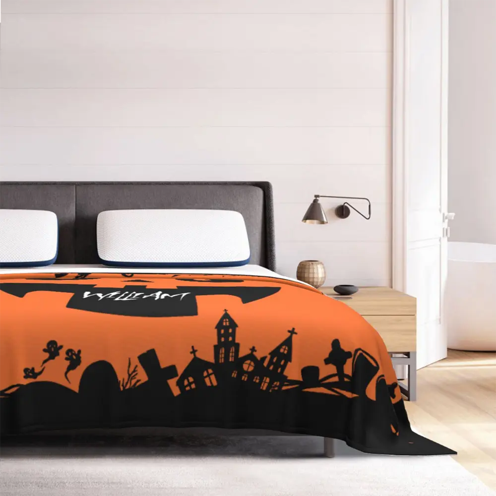 Halloween-themed personalized flannel blanket on bed, highlighting plush texture, pumpkin face centerpiece, and decorative motifs.