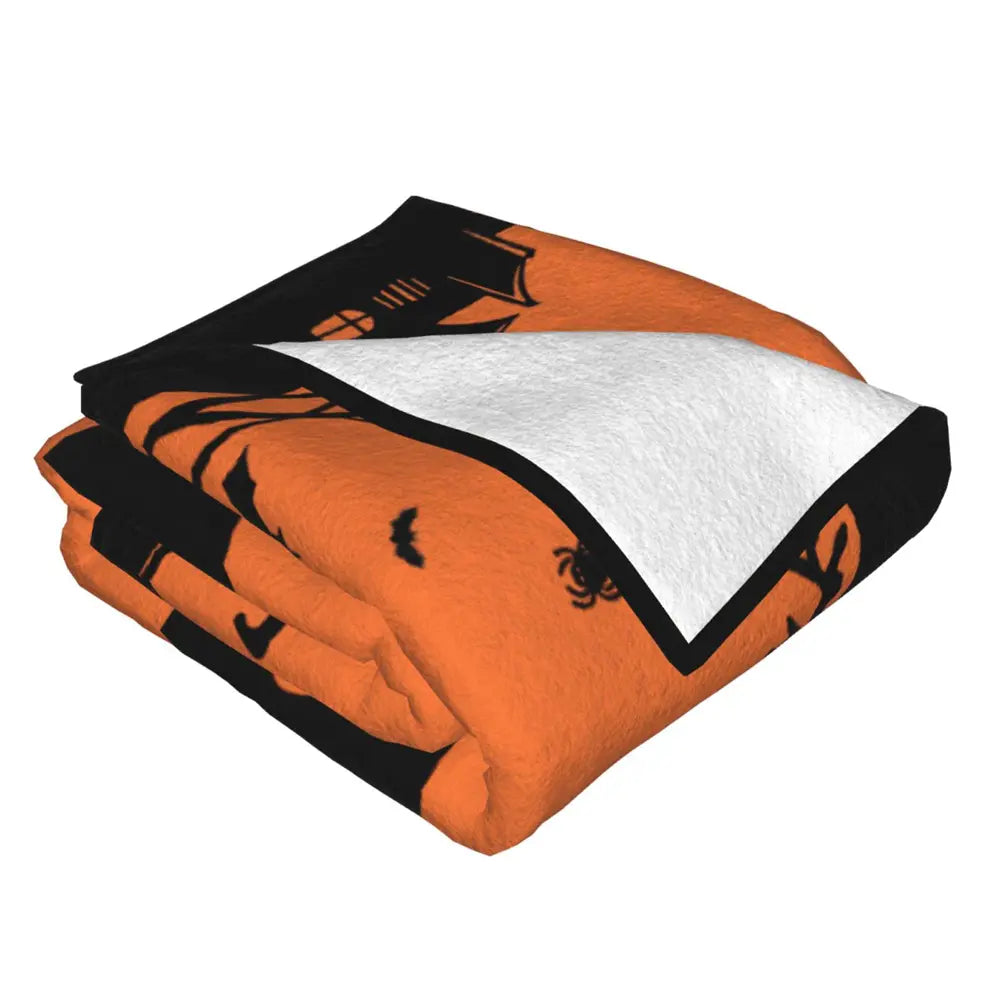 Custom Halloween blanket neatly stacked, featuring plush flannel material, pumpkin face design, and personalized name option.